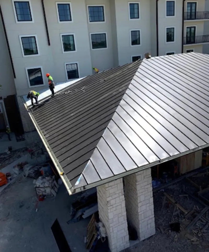 Crew installing standing seam metal roof panels on a commercial project in Kearney